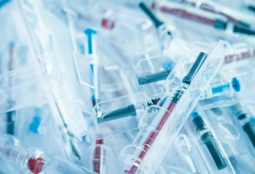 Close-up of various plastic medical components including syringes, molded using clean, contaminant-free resins in a sterile manufacturing environment.