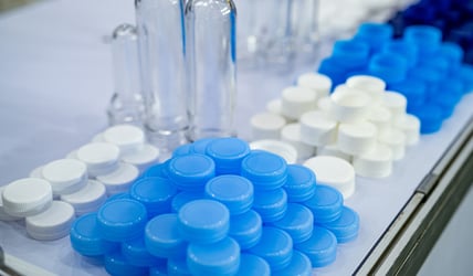Close-up of injection-molded bottle caps in different colors, produced using a hot runner system, showcasing clean color transitions with Asaclean® purging compounds.