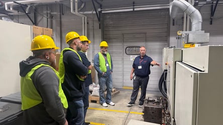 Attendees observing live screw pull demonstration on an injection molding machine.