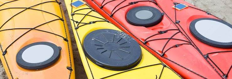 Four colorful kayaks laying on the ground